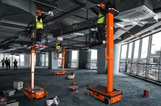 Plataformas de mástil vertical en una obra, con operarios trabajando en la cesta
